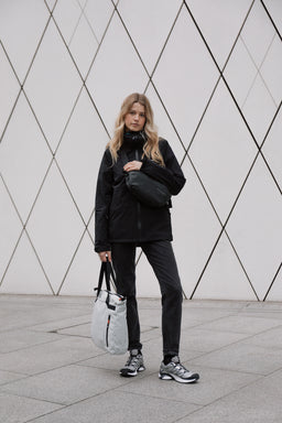 A woman holding an Off White Ultra Light packable bag and wearing a black crossbody bag