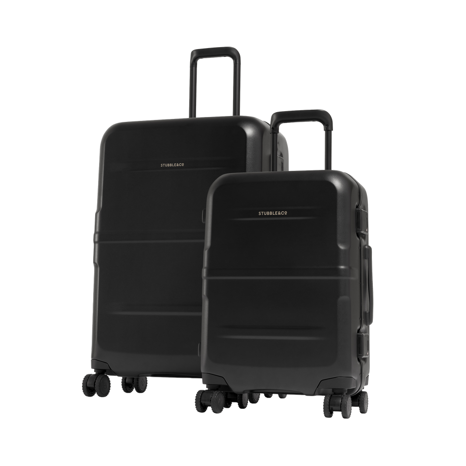 Two black hardshell suitcase bundle set. One large and one small suitcase. One in front of the other.