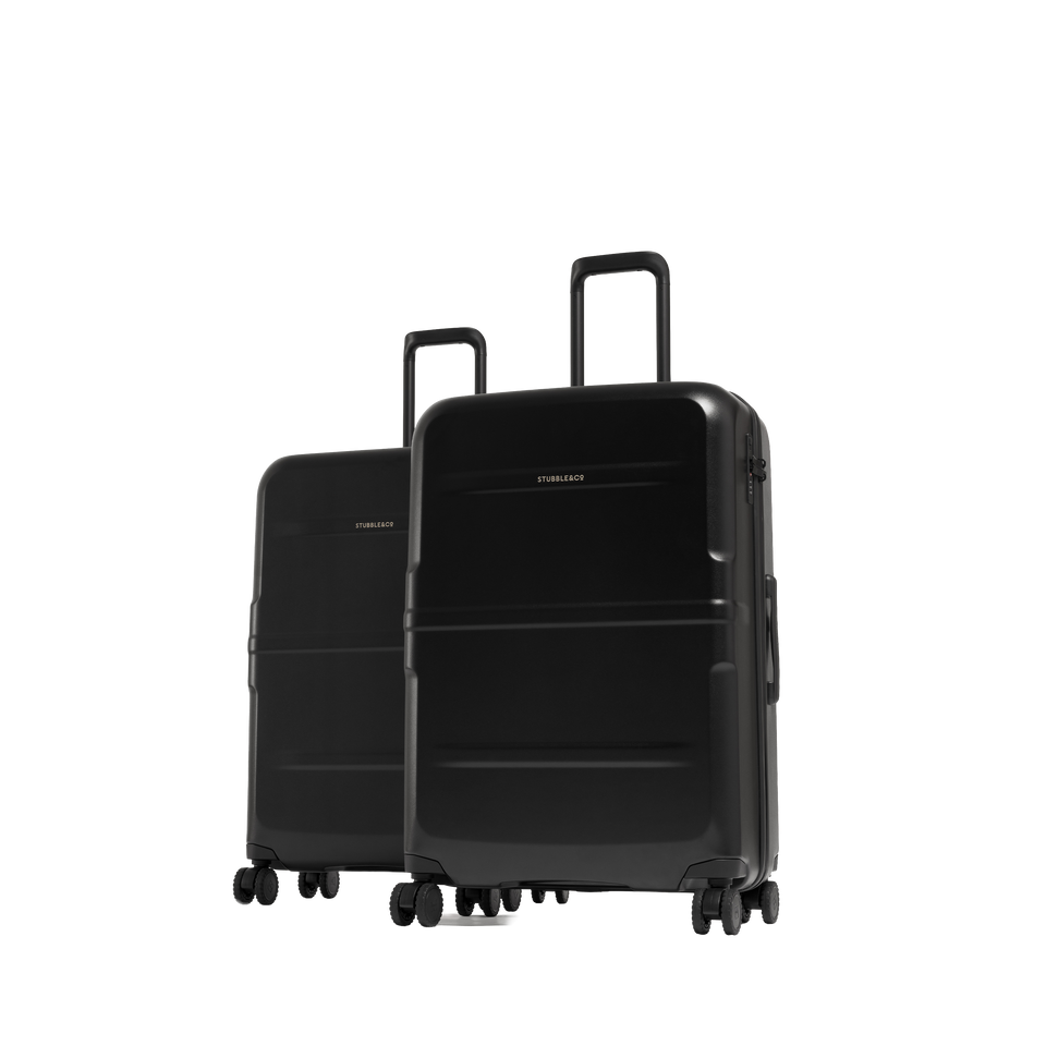 Two black hard-shell spinner suitcases standing upright on a clean white studio background, with the larger suitcase in front and a smaller one behind. 