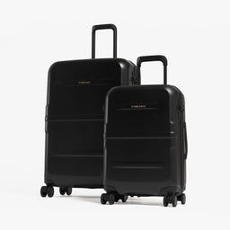 Two black hard-shell spinner suitcases, one larger and one smaller, standing upright on a light gray studio background. [All variants]