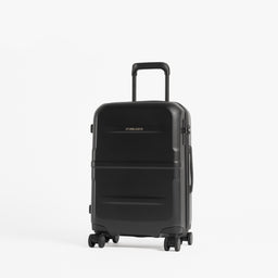 A black hard-shell spinner suitcase with an extended telescoping handle, standing upright on a light gray studio background. [All variants]