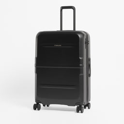 A black hard-shell spinner suitcase with an extended telescoping handle, standing upright on a light gray studio background. [All variants]