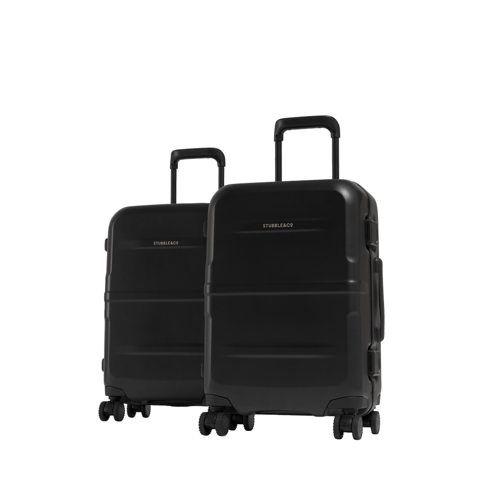 Two hard-shell spinner suitcases in matte black, shown on a plain white background. The larger suitcase in front has its telescoping handle extended, and the smaller matching suitcase stands behind it.