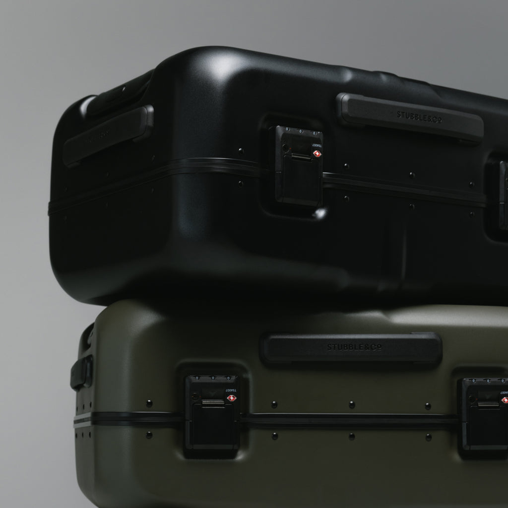 Two hard-shell suitcases stacked vertically against a neutral gray studio background.