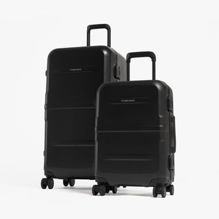 Two hard-shell spinner suitcases in black, one larger and one smaller, standing upright on a clean white studio background. [All variants]