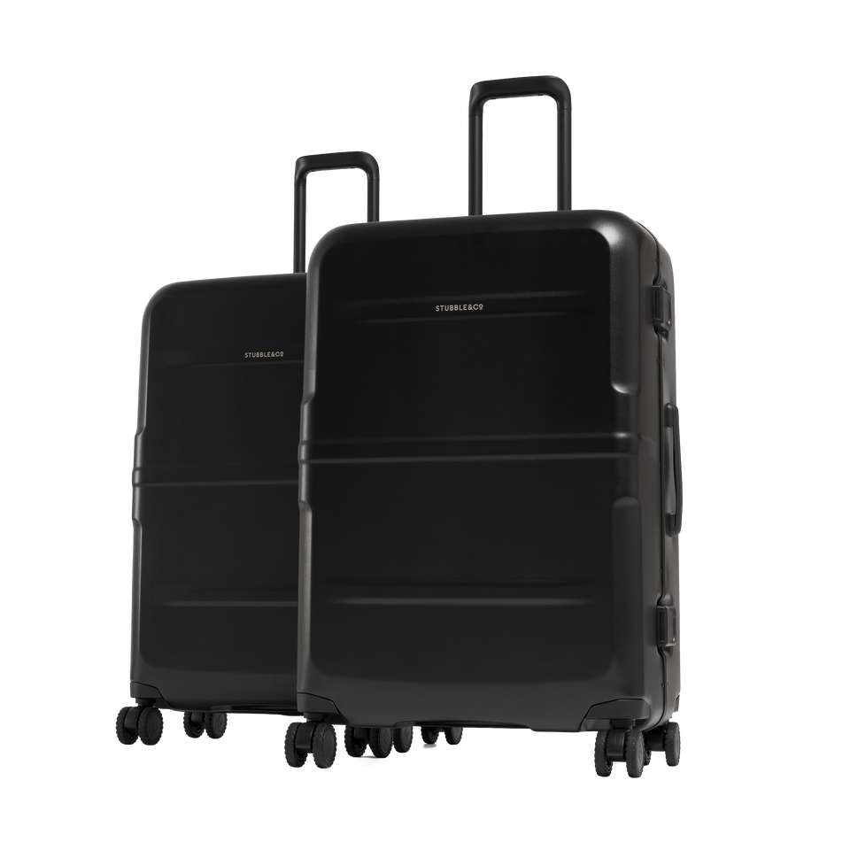 Two black hard-shell spinner suitcases with telescoping handles, shown on a clean white background. The larger suitcase in front and the smaller one behind.