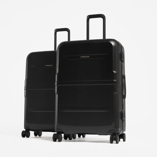 Two black hard-shell spinner suitcases standing upright on a light gray studio background. [All variants]