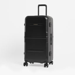 A black hard-shell spinner suitcase with an extended telescopic handle, standing upright on a light gray studio background.  [All variants]