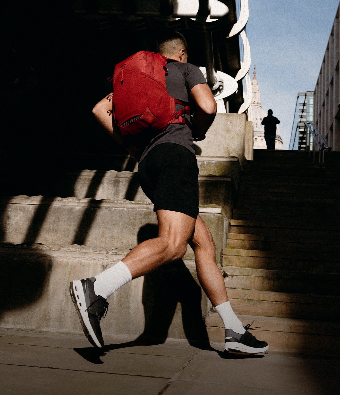 A man running up to some stairs wearing a magma motion backpack 20l on his back