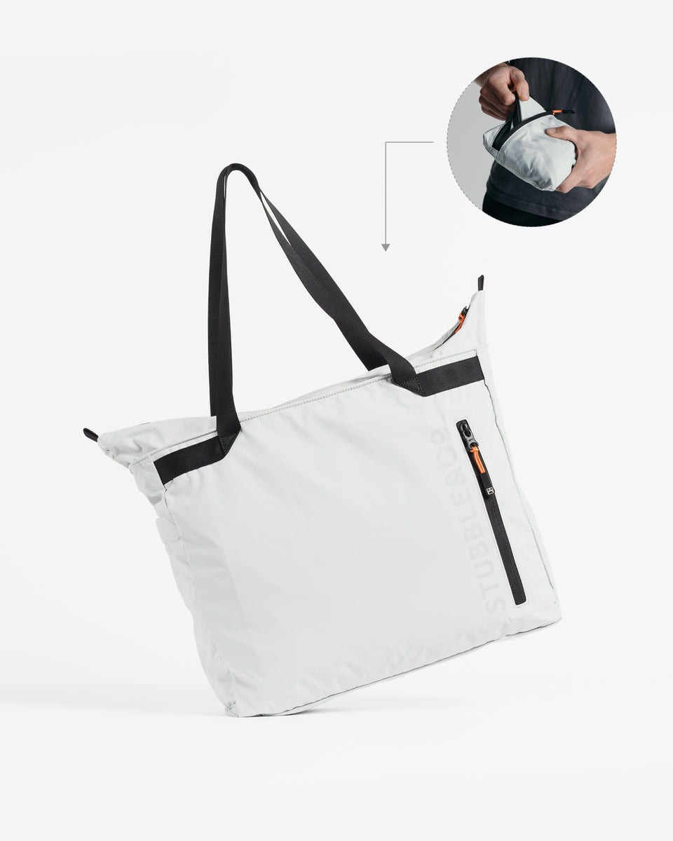 A packable Ultra Light Tote Bag with small annotation of how it backs into a pouch