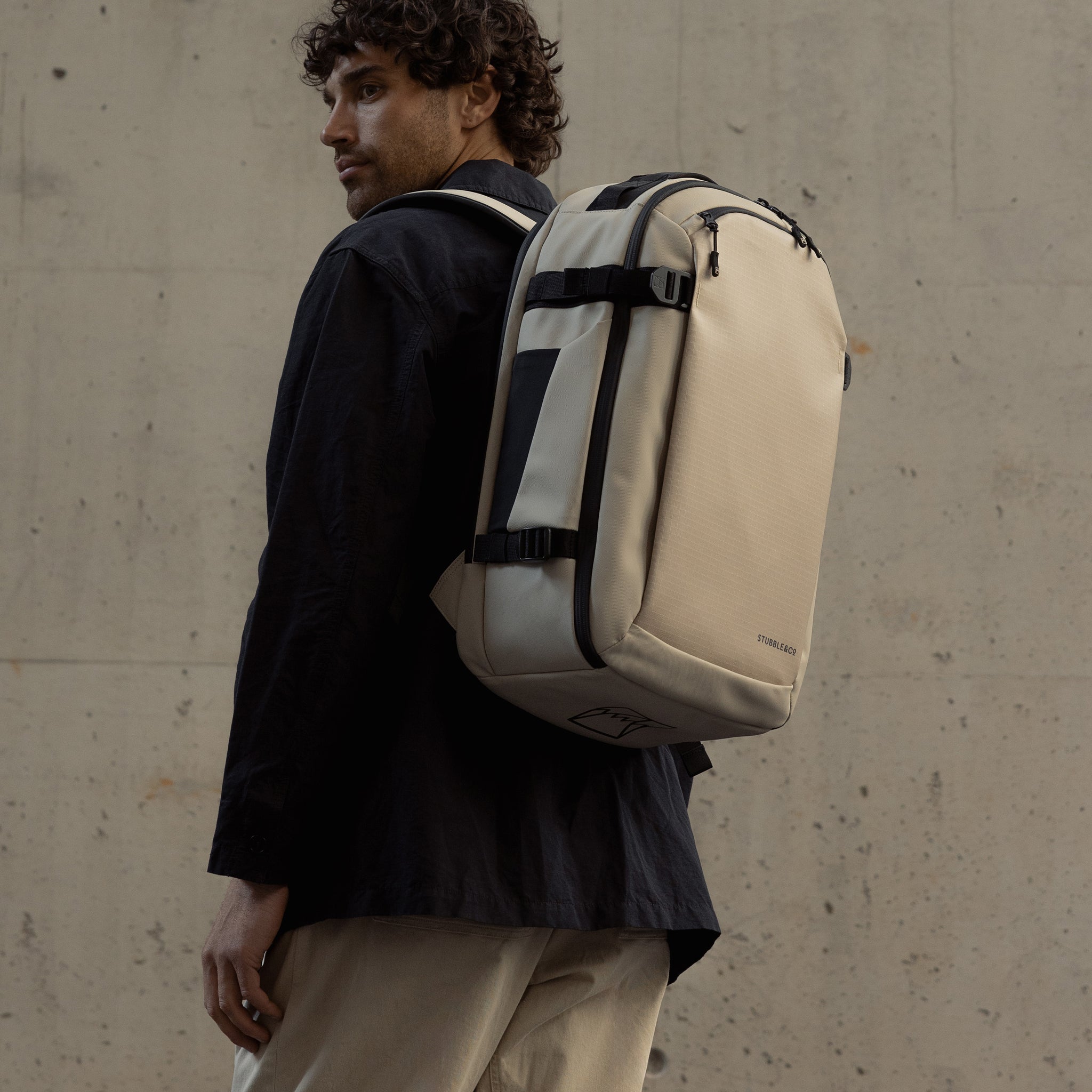 A man facing away wearing a hybrid backpack 30l on his back in sand
