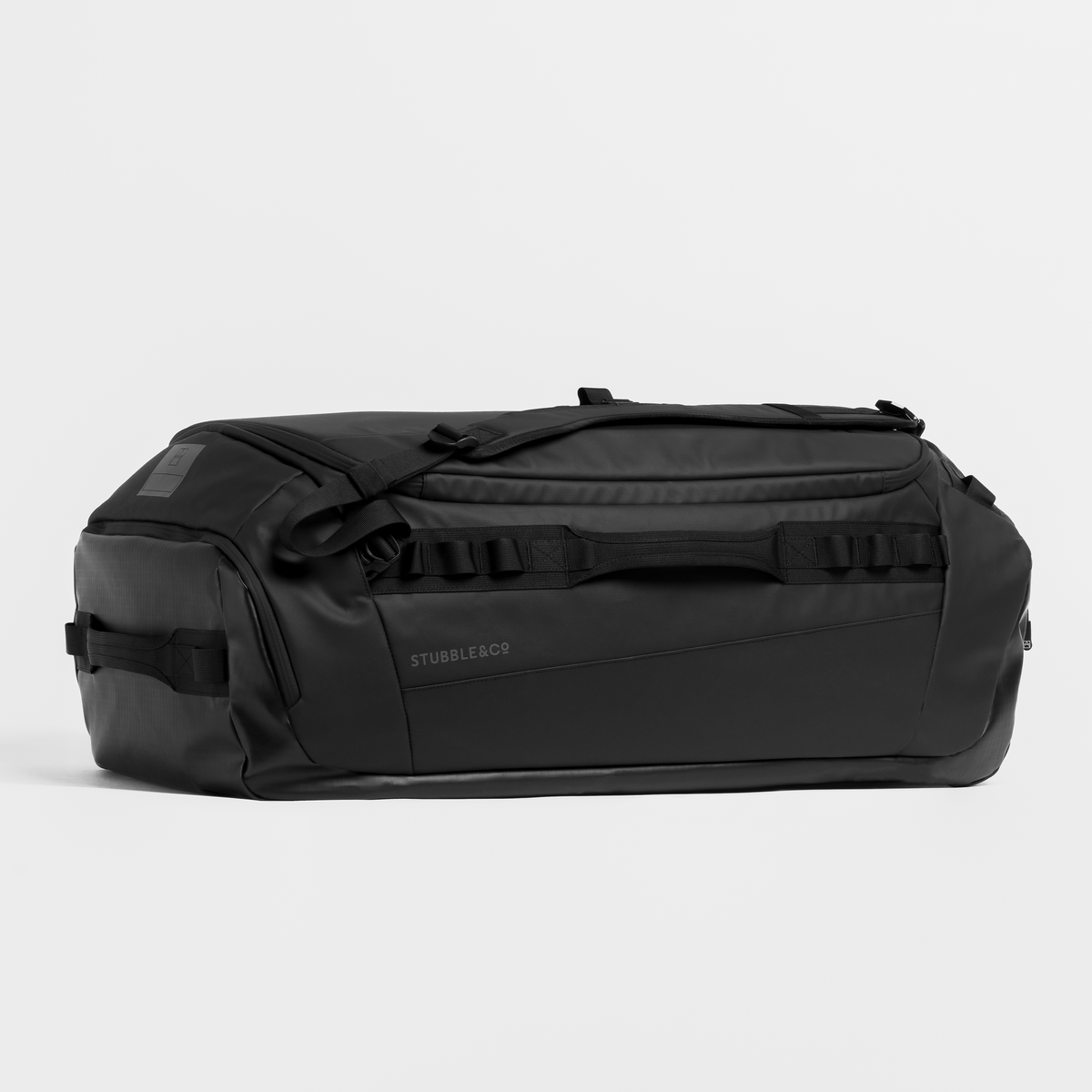 A black duffel bag with multiple compression straps and a top handle, photographed from the side against a light gray studio background.