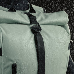 Close up view of the waterproof Roll Top Backpack in Matcha green with water spray