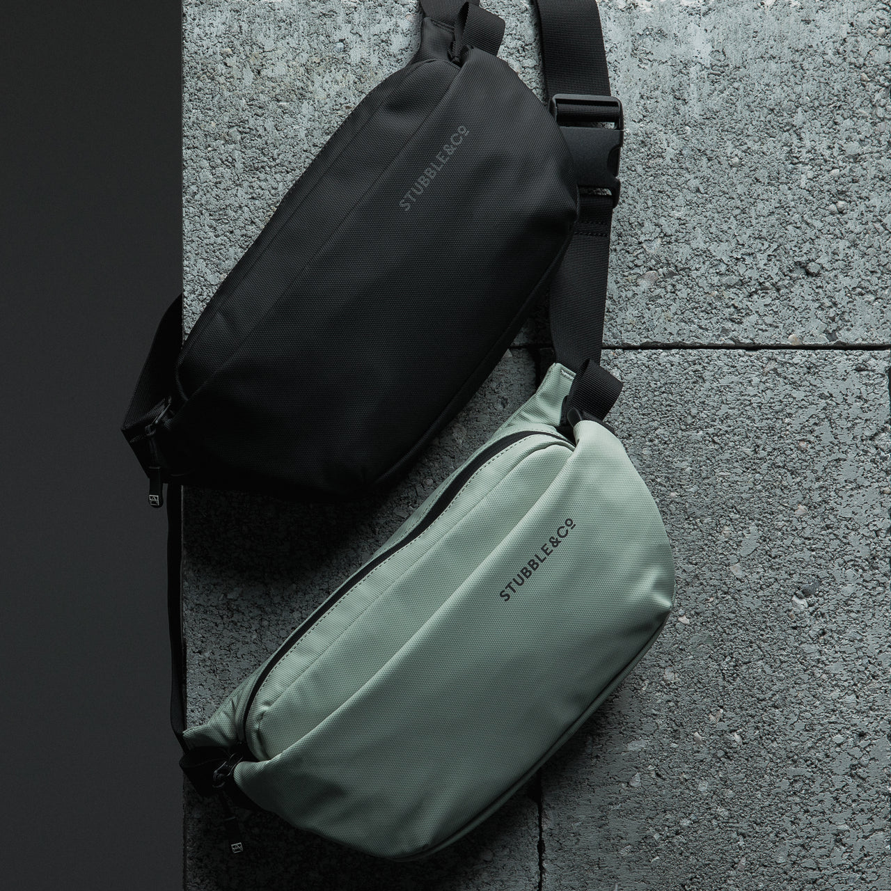 A Matcha green and all black crossbody hanging on a concrete block