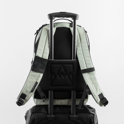Back view of the Everyday Backpack in Matcha on a suitcase using a trolley sleeve