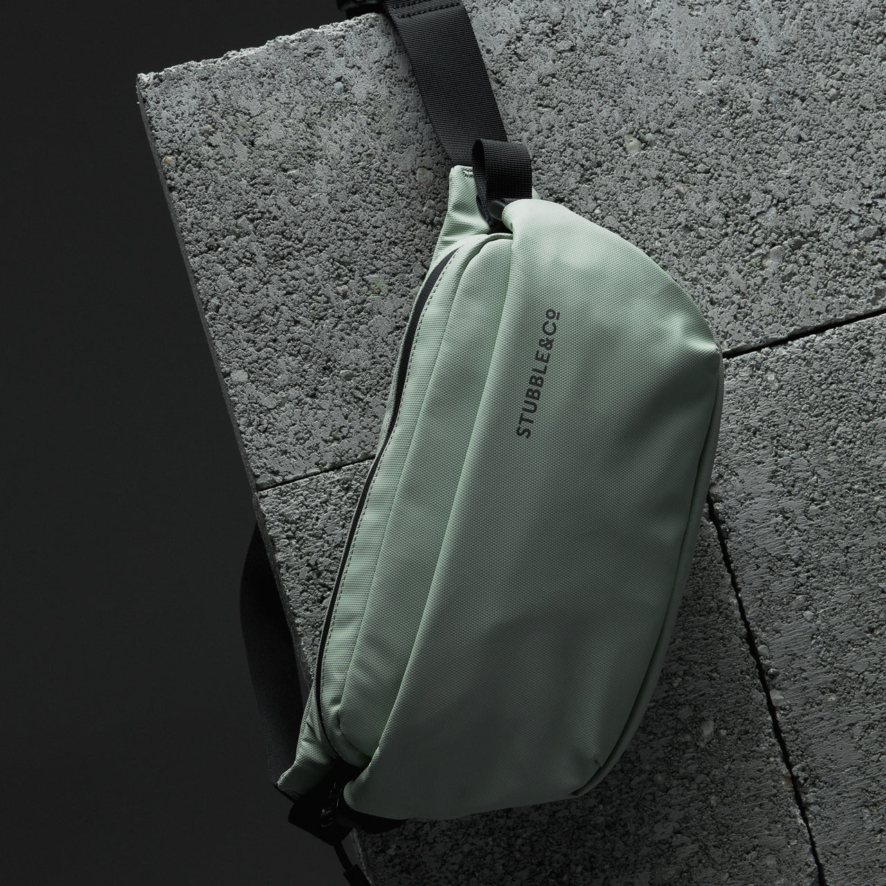 Front view of a Matcha green Crossbody bag on a concrete surface