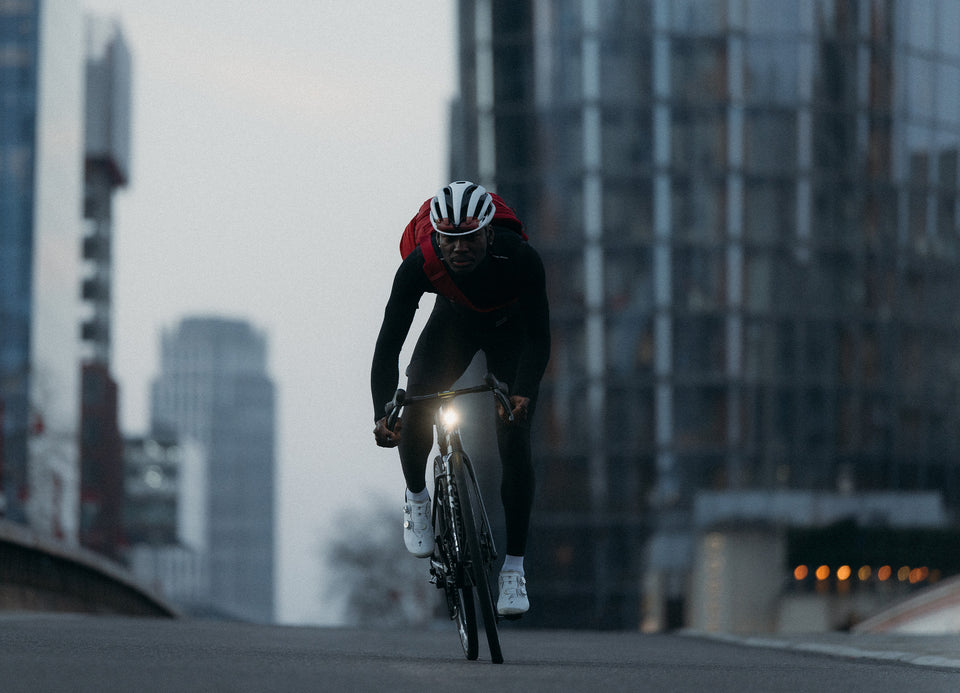 A man cycling down a road wearing a helmet and magma motion sling 15l on his back