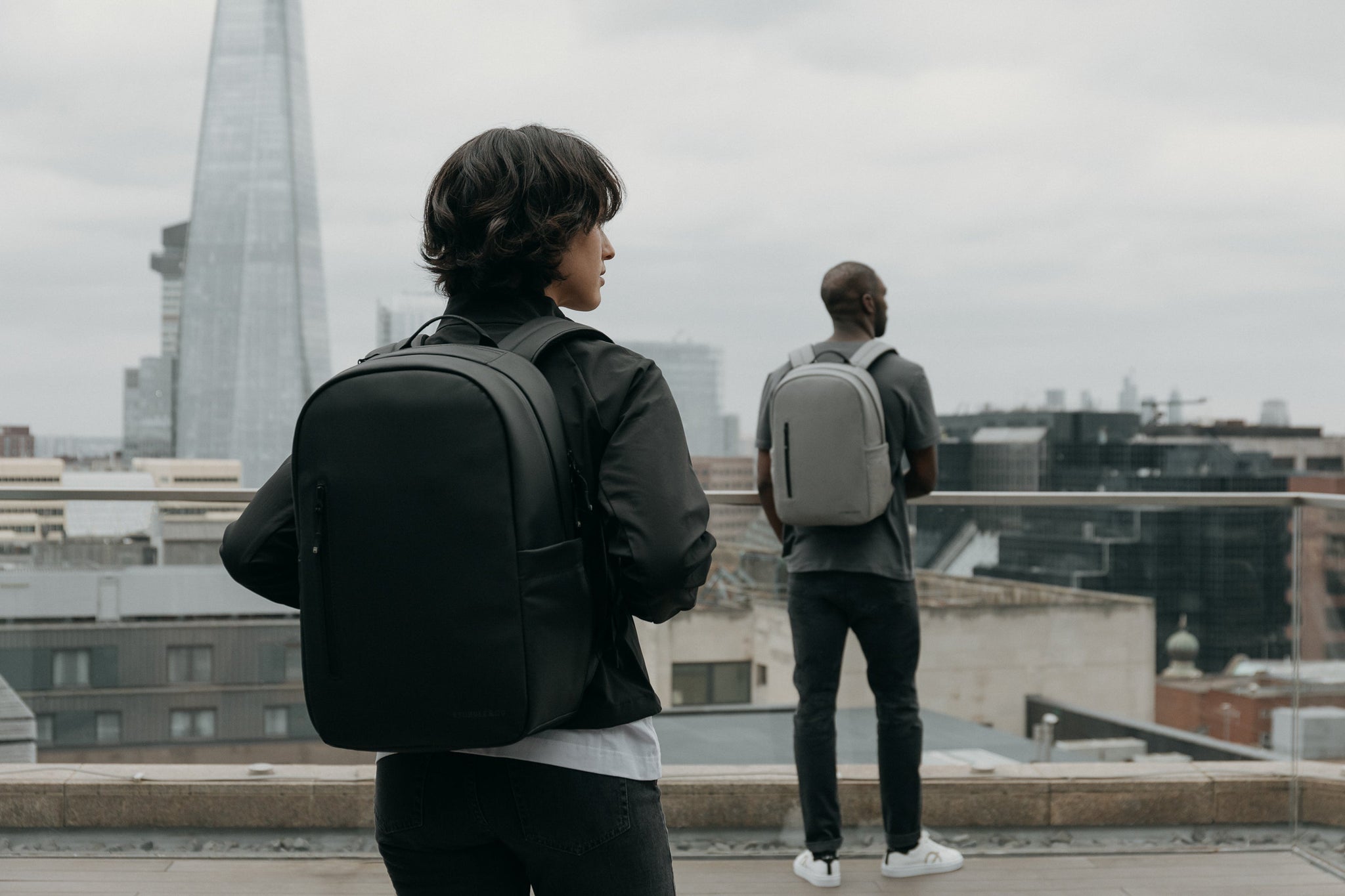 Women with black backpack standing with a man looking at a city