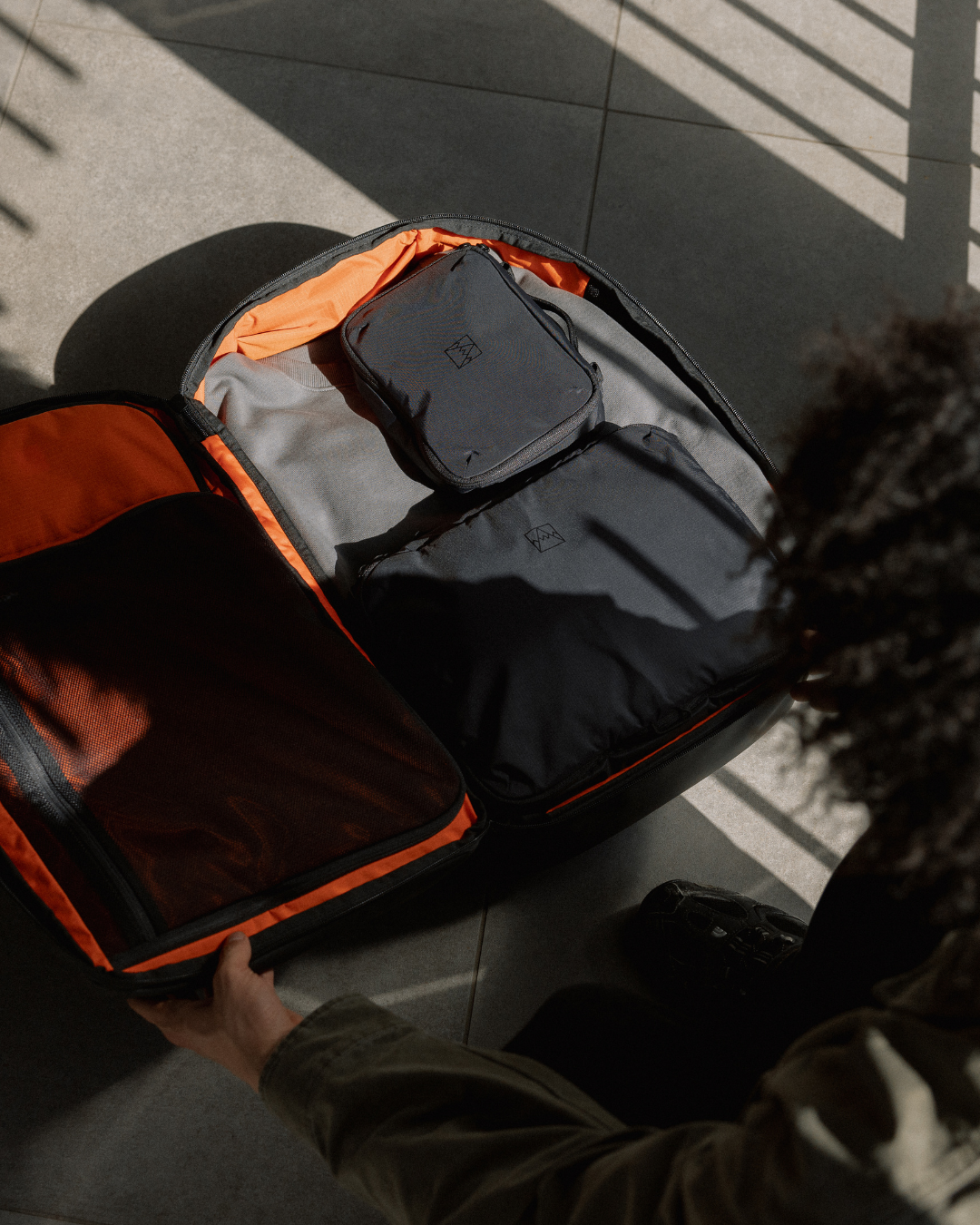 Overhead shot of man packing their travel backpack with clothes and packing cubes