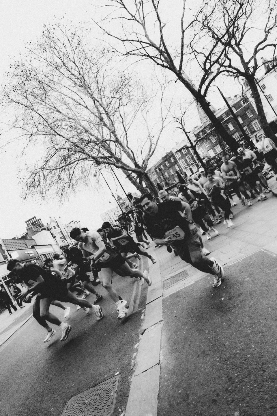 A black and white photo of runners setting off on a run at the start of a race