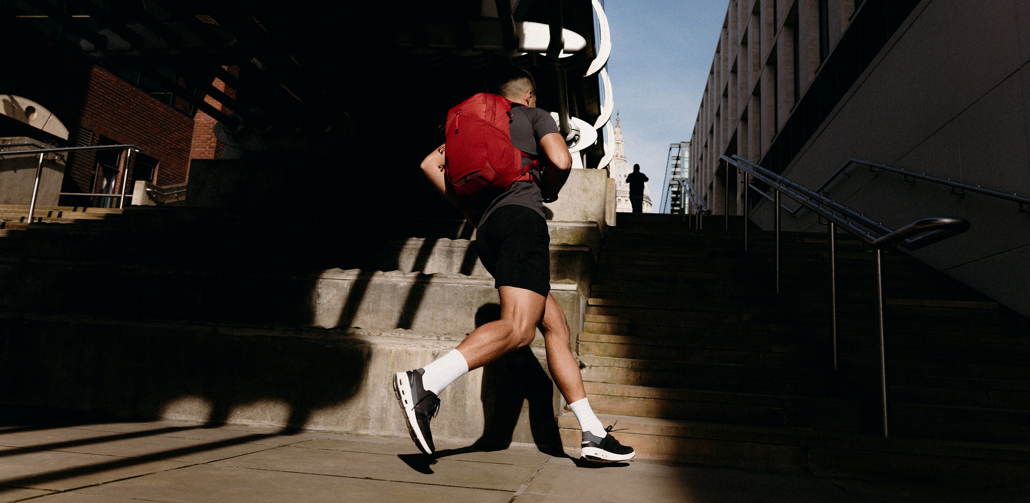 A man running up stairs with a motion backpack 20l on his back