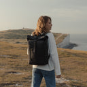Women wearing an All Black Roll Top backpack standing on top of a white cliff