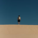 Man stood at the top of a dune with back to camera wearing The Sand Roll Top