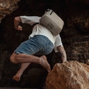 Man jumping of a rock wearing The Sand Roll Top