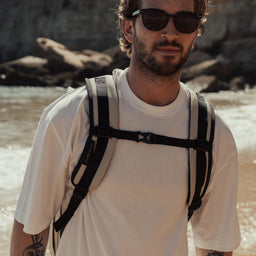Man walking towards the camera wearing The Sand Roll Top with the chest strap