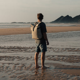 Man stood on beach with back to camera wearing The Sand Roll Top