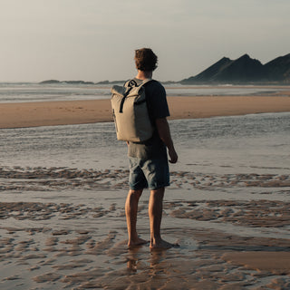 Man stood on beach with back to camera wearing The Roll Top in Sand