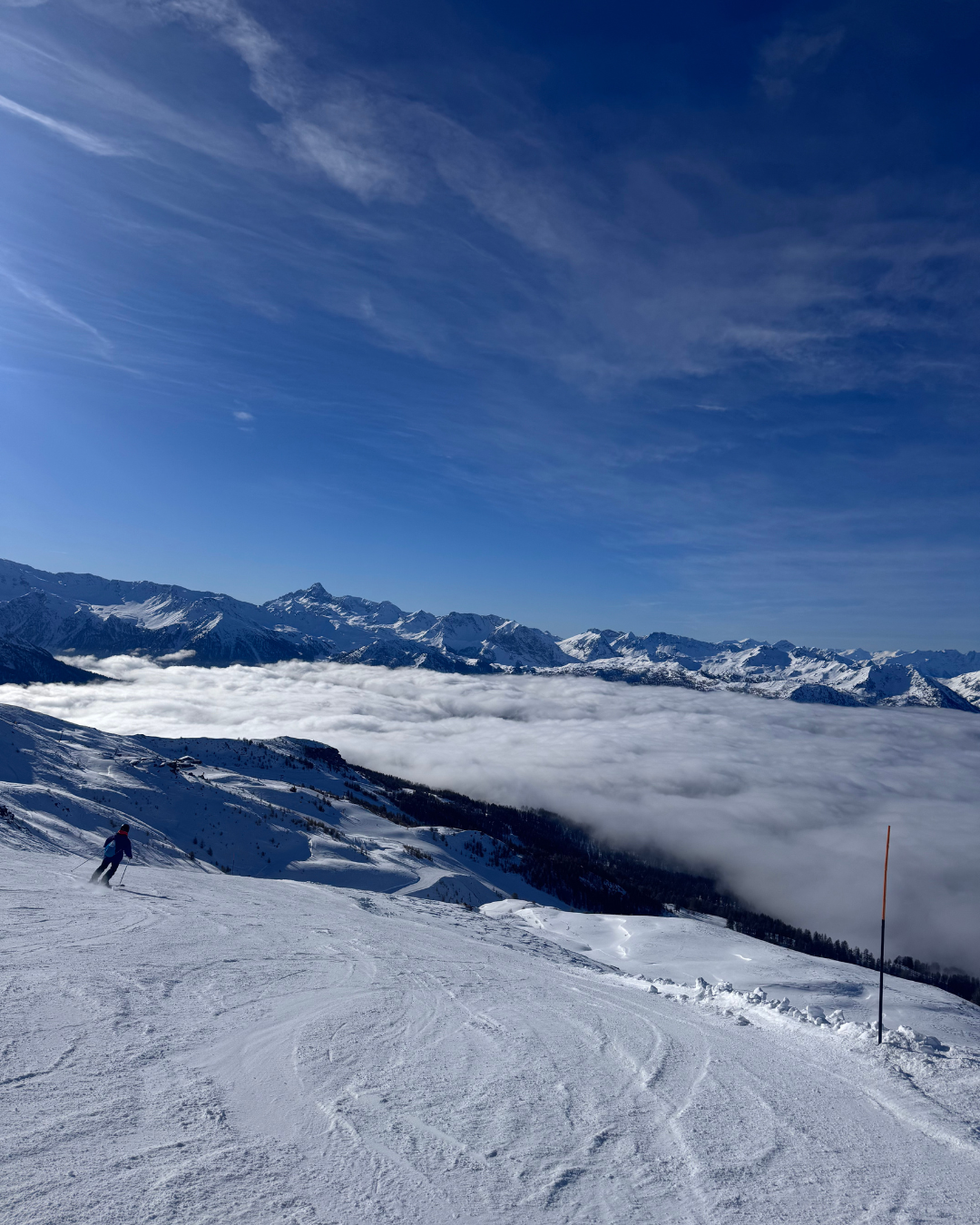Someone skiing down a snowy slope against a blue sky backdrop