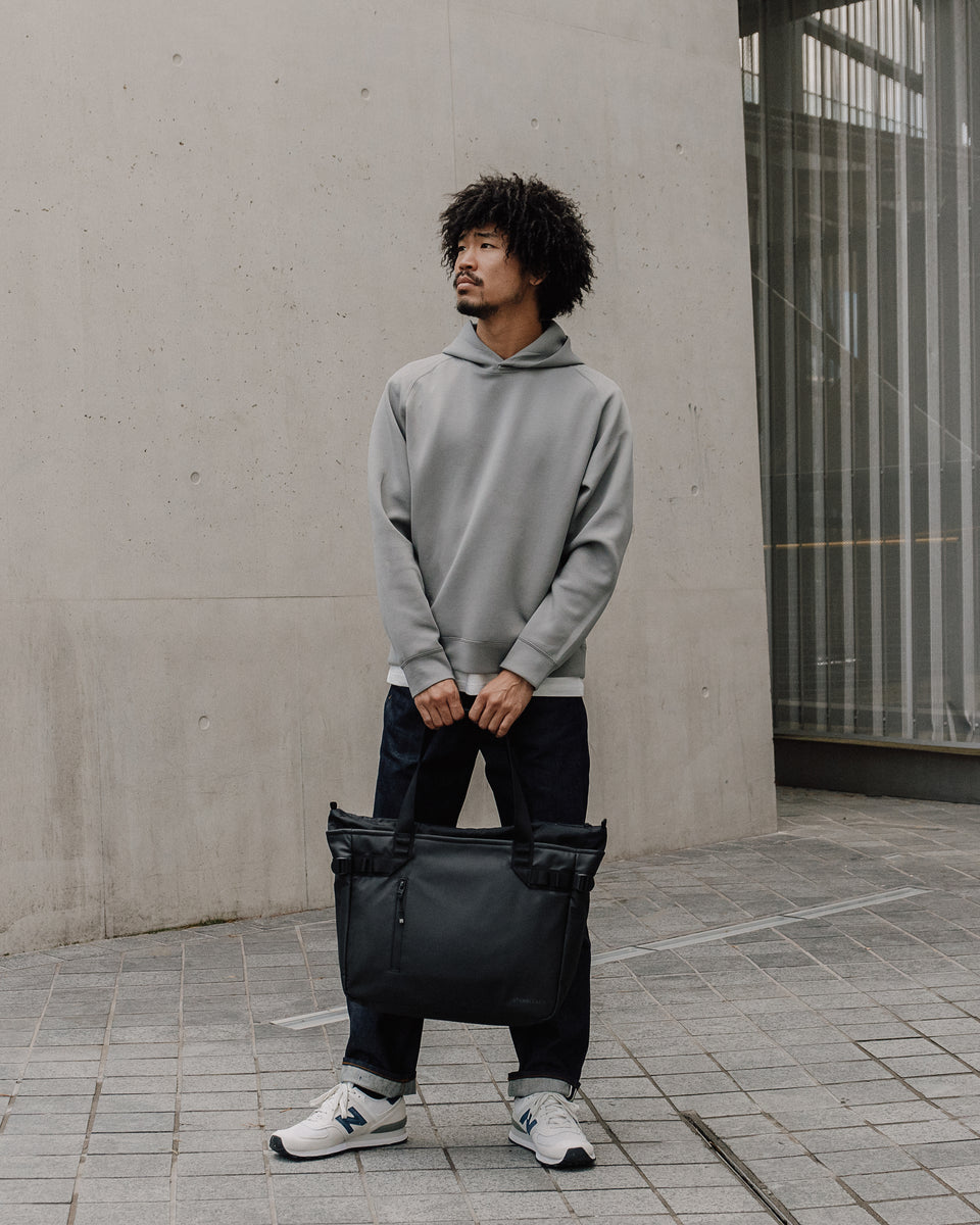 Person holding a black tote bag