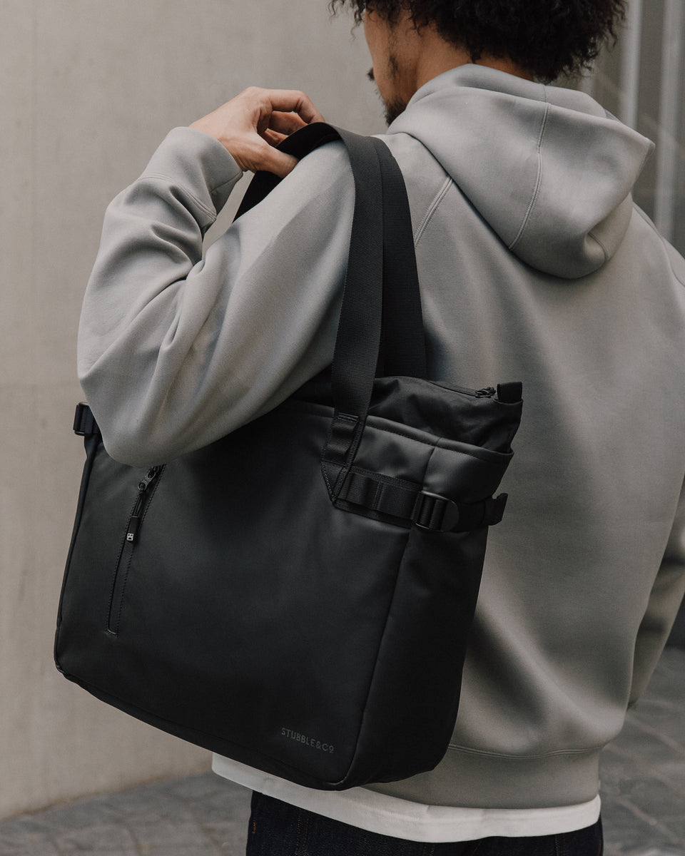 Close up of person carrying a black tote back and wearing a grey jumper