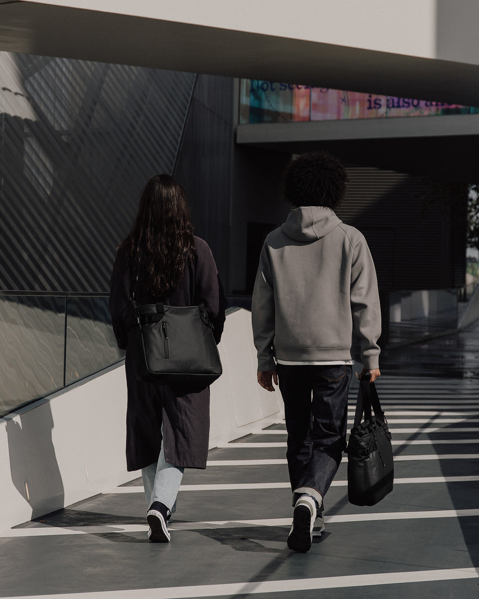 two people carrying black tote bags