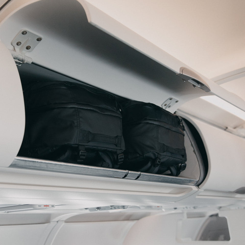 two All Black Adventure bags in the overhead lockers on an airplane