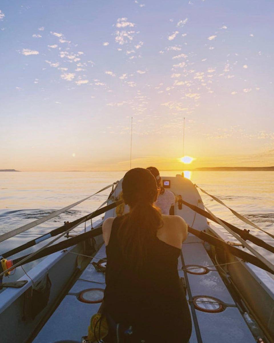 two woman rowing on the sea during sunset