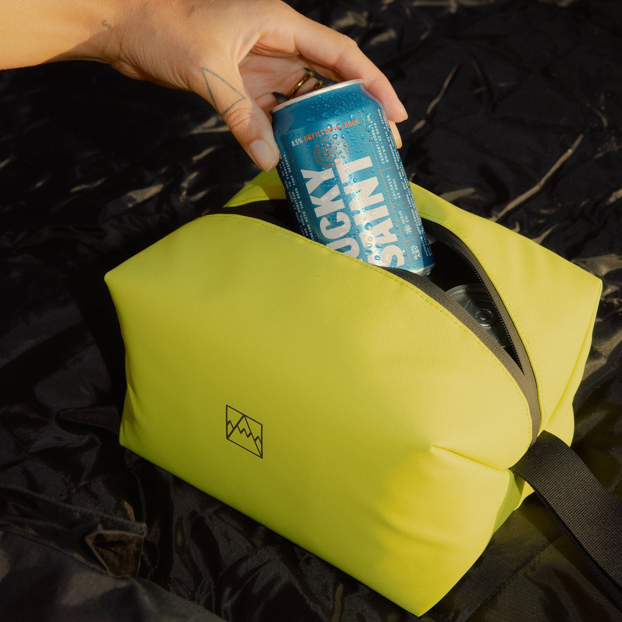 A woman picking out a lucky saint beer can from the Volt Beer Bag by Stubble & Co