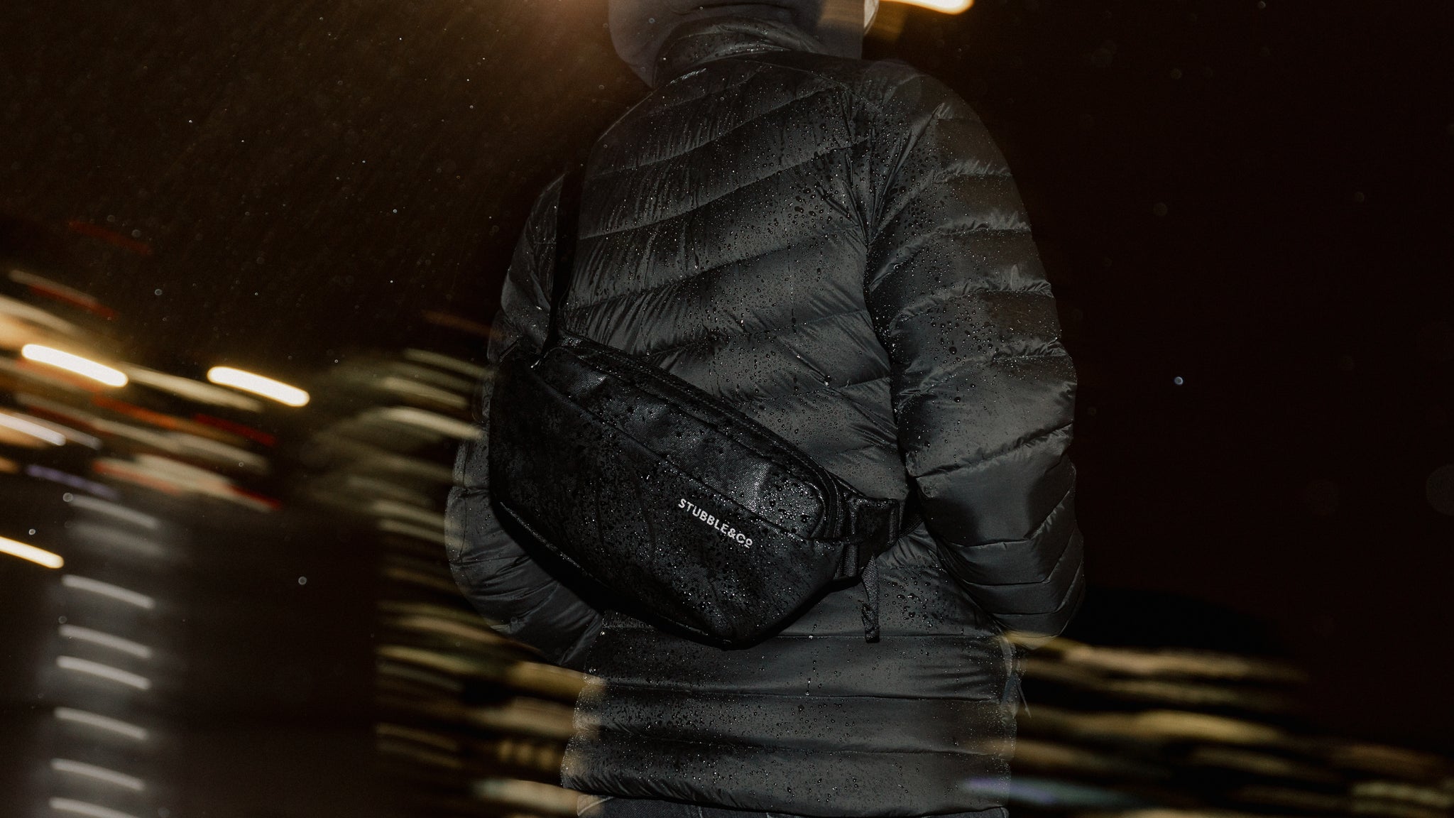 close up of the back of a person wearing a black crossbody bag at night
