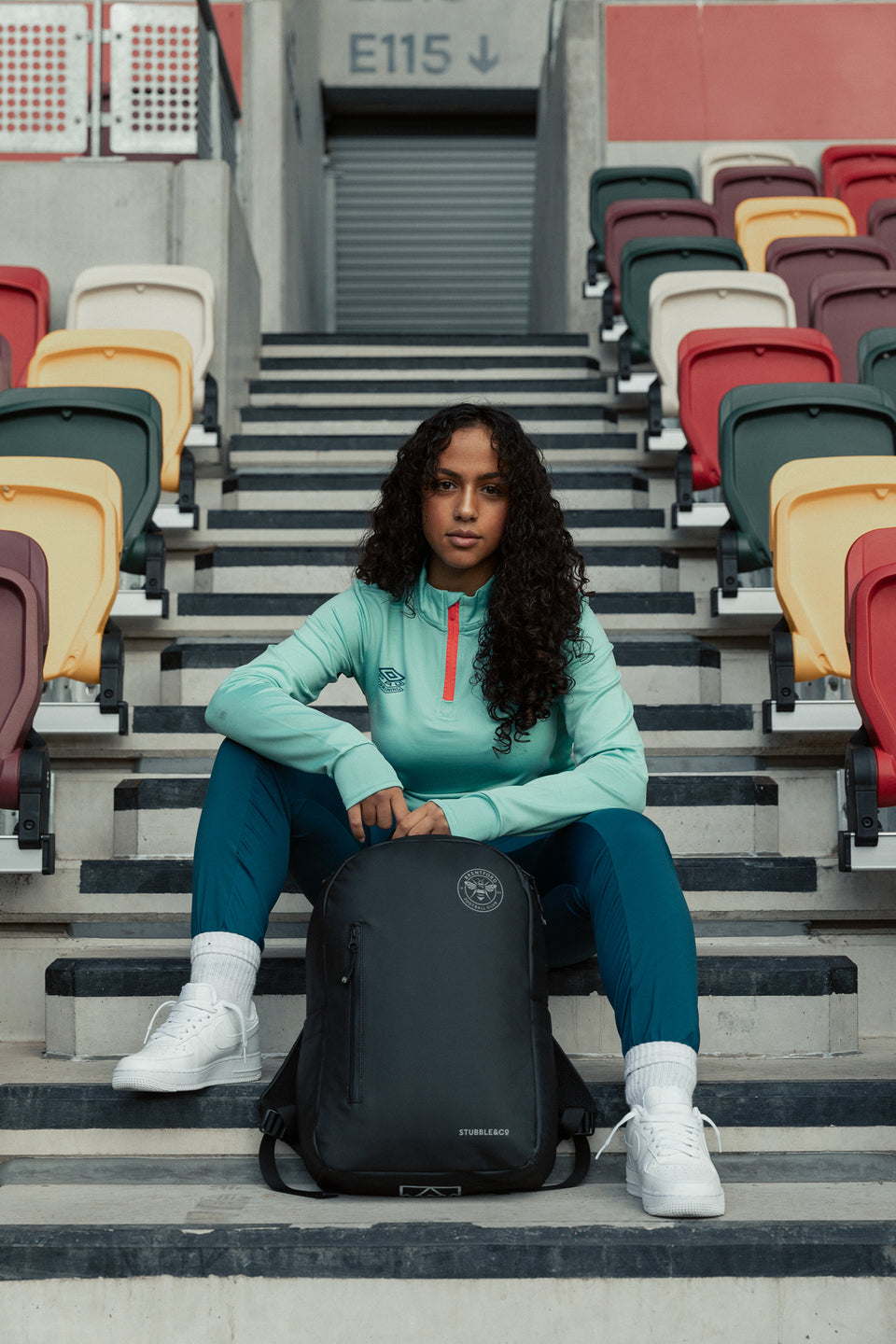 female sitting on stadium steps with a black backpack