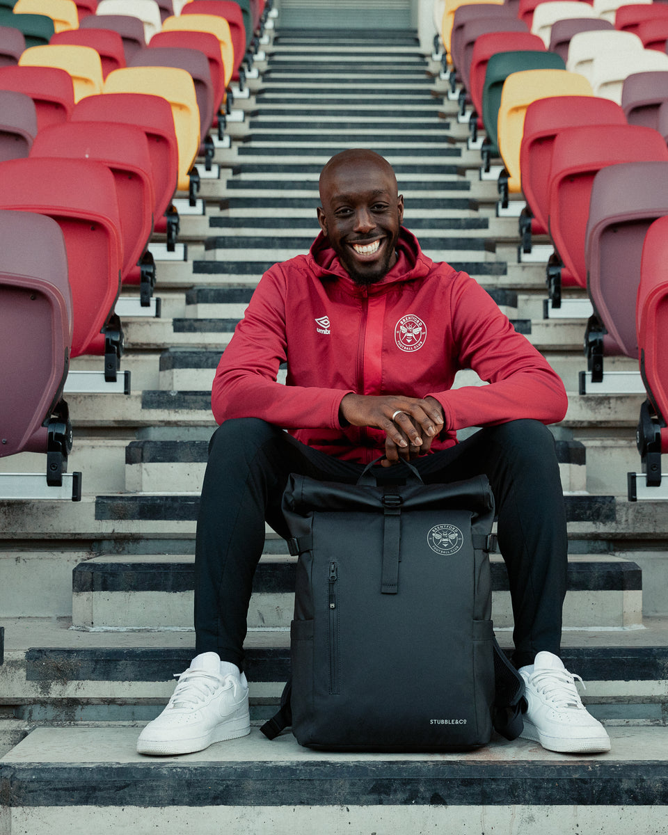 brentford football player sitting on the stadium steps with a black backpack