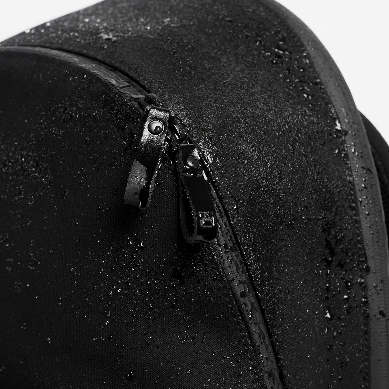 A studio shot close up of the water resistant material on the commuter backpack 25L in All Black