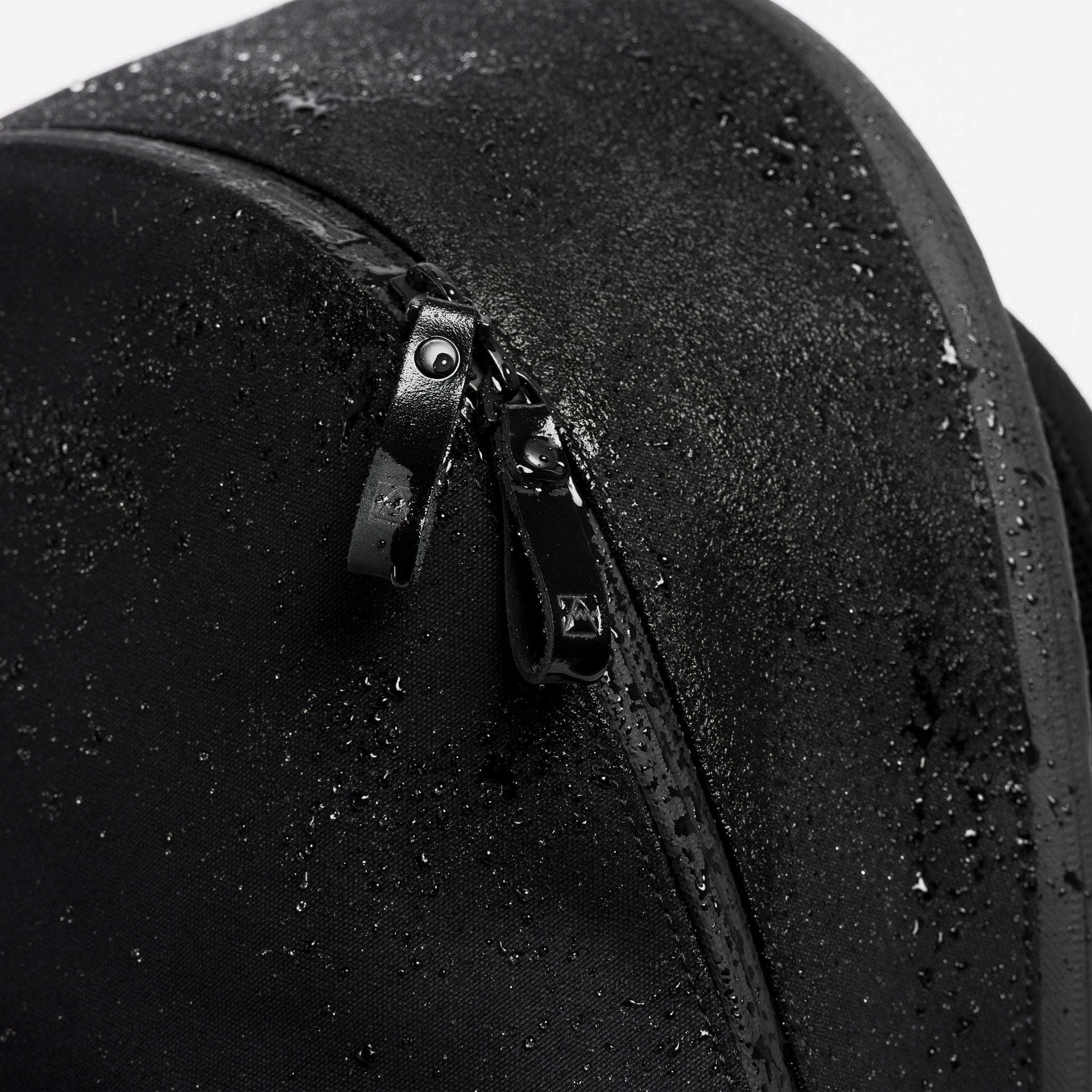 A studio shot close up of the water resistant material on the commuter backpack 25L in All Black
