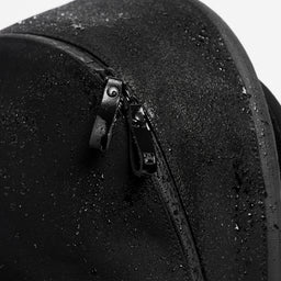 A studio shot close up of the water resistant material on the commuter backpack 25L in All Black