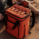 The Cooler Backpack in Ember Orange on a beach