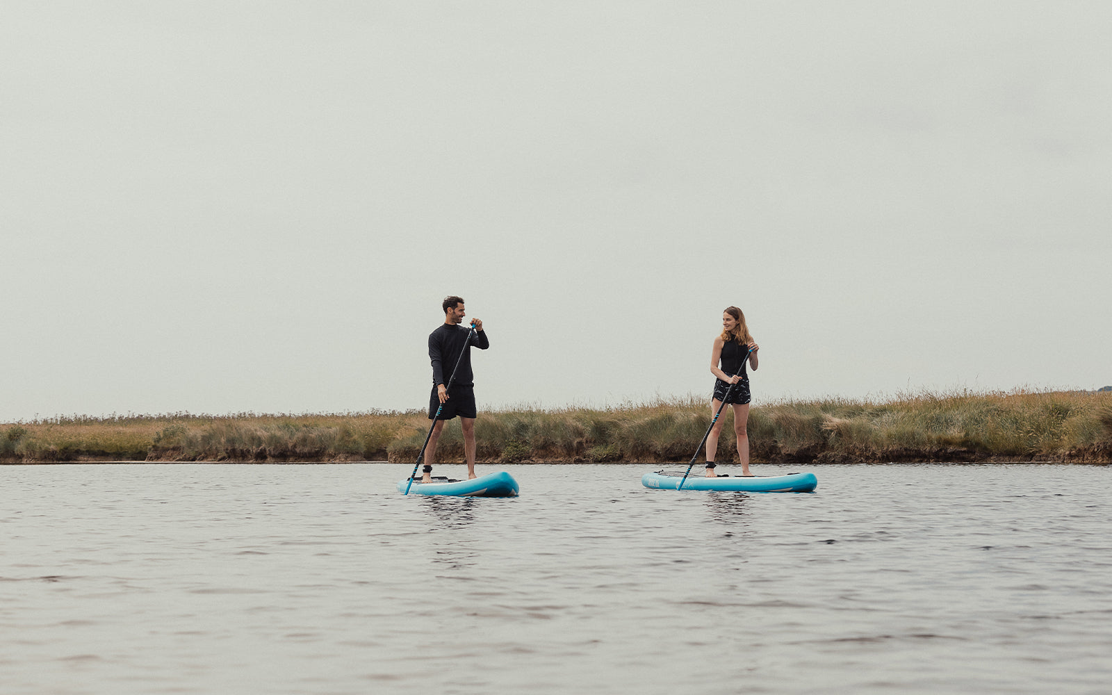 A couple paddle boarding on a river