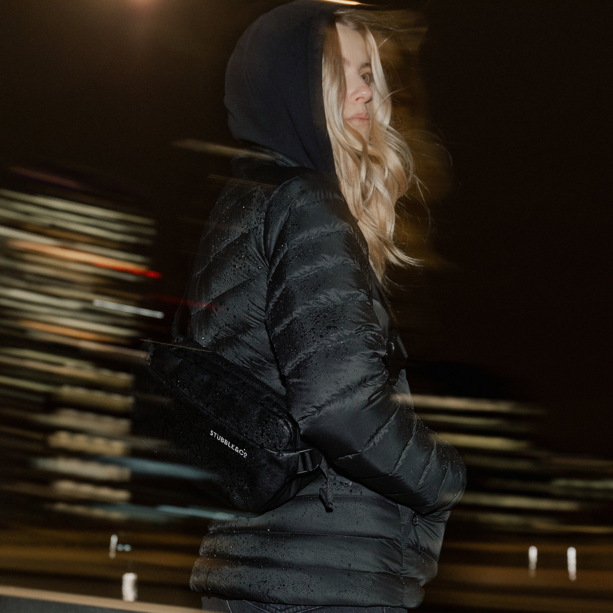 A woman wearing an All Black Crossbody on her back in the rain
