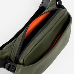 A studio shot of an Urban Green Crossbody showing the interior orange lining and front pockets