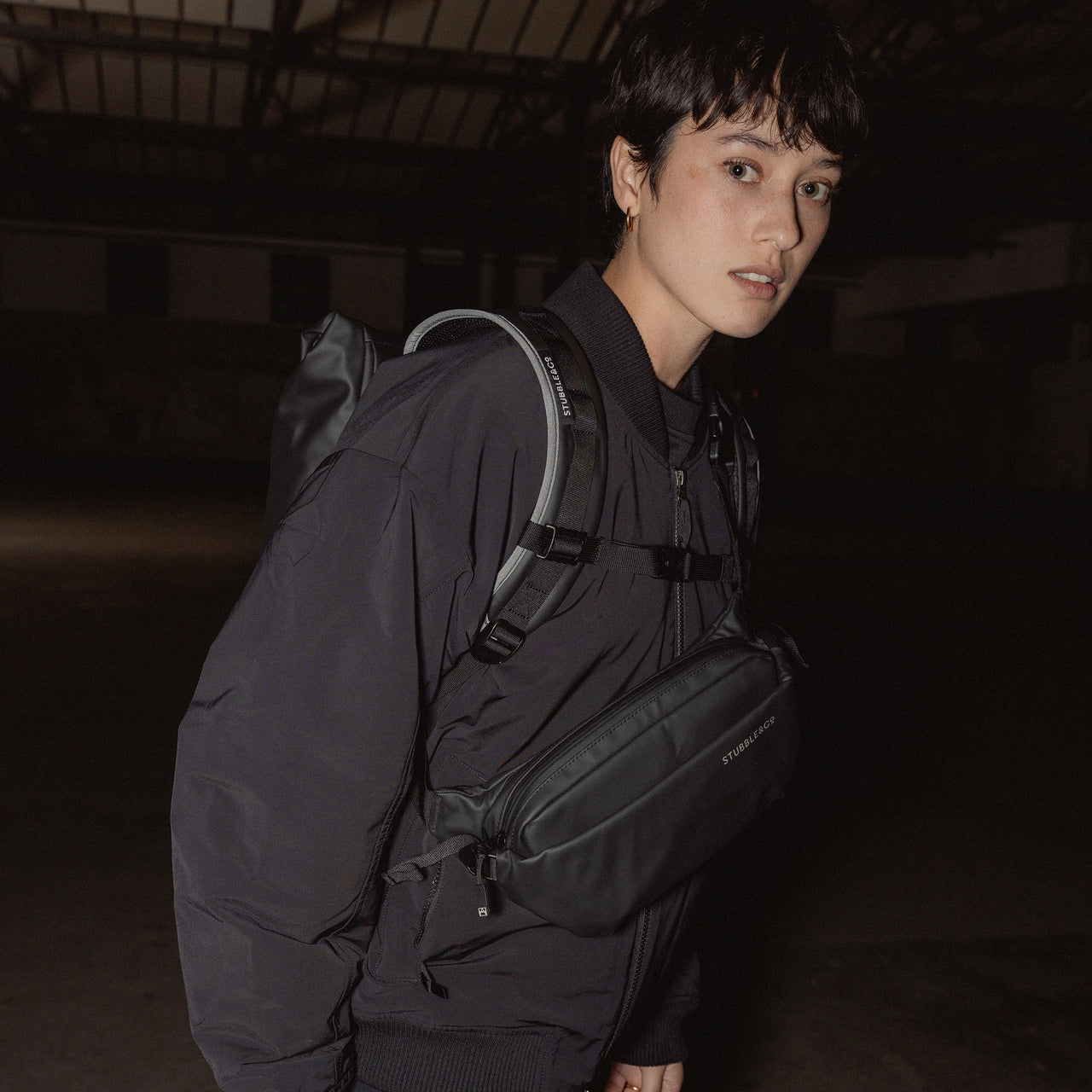 A woman wearing and All Black Crossbody on her front and roll top on her back