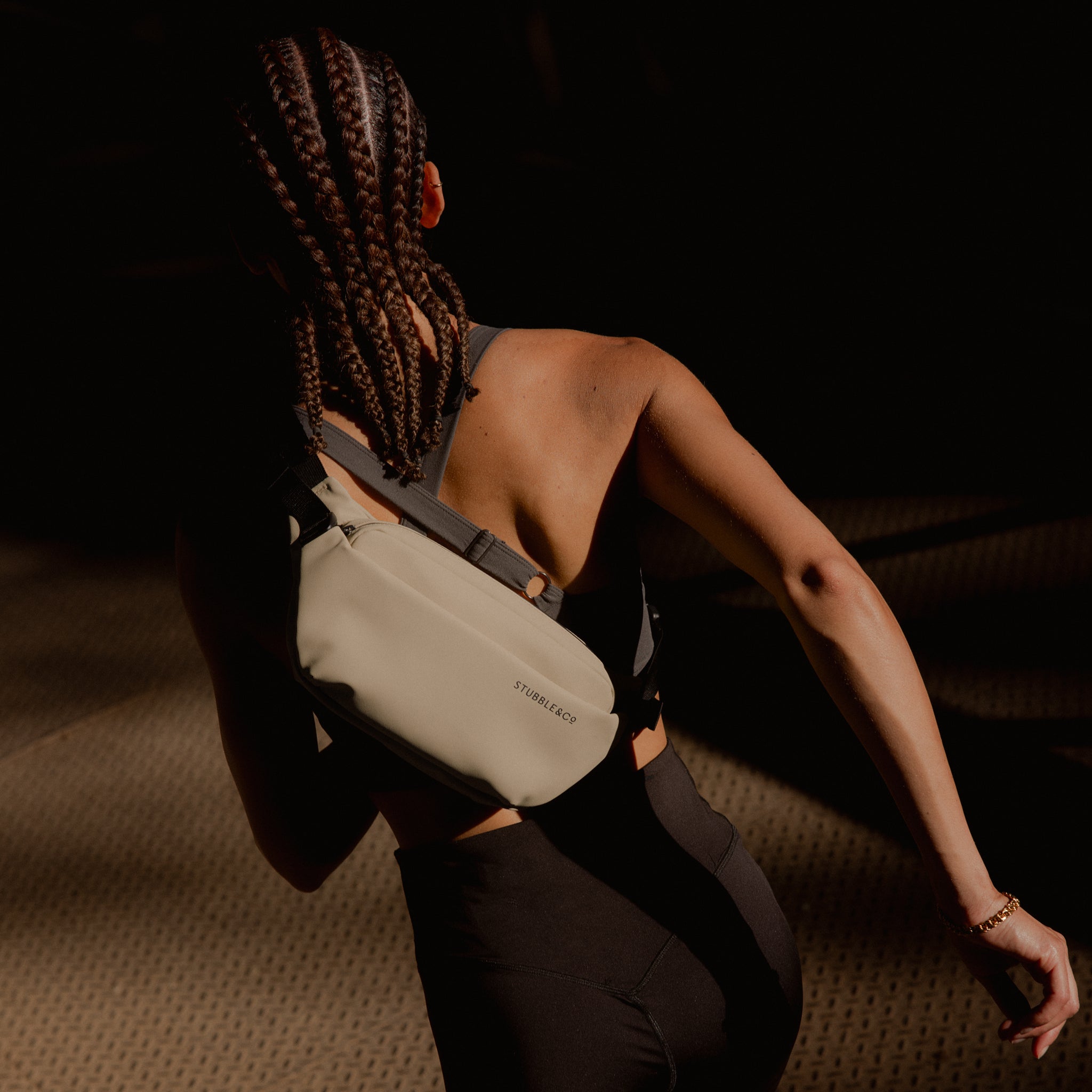 A woman running with a Sand crossbody on her back